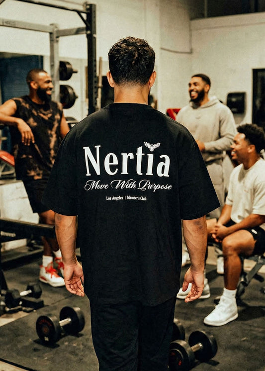 Person wearing a black 'Nertia' t-shirt in a gym setting with other people.