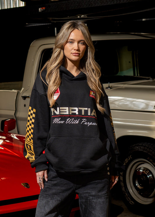 Person wearing a hoodie with branding in a garage setting with vehicles.