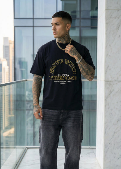 Man wearing a black t-shirt with text and graphics, standing on a balcony with modern architectural background.