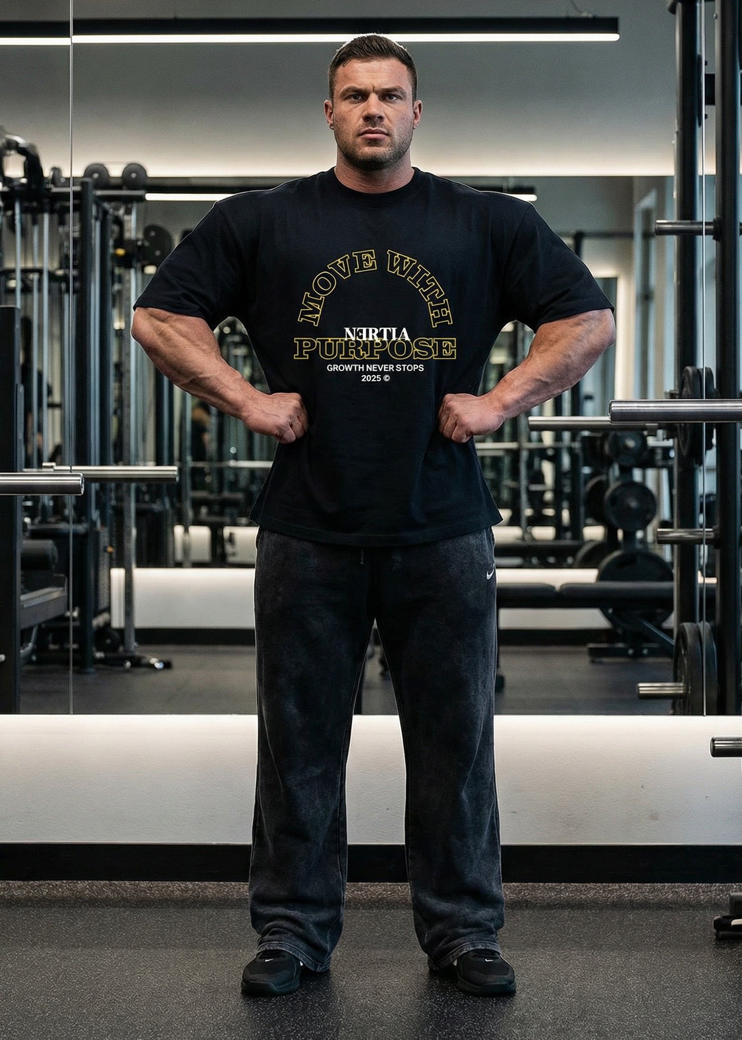 Man wearing a black t-shirt with visible branding in a gym setting