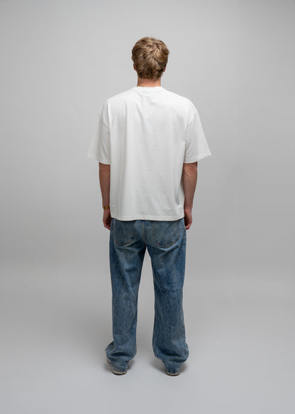 Person wearing a plain white t-shirt and blue jeans on a gray background