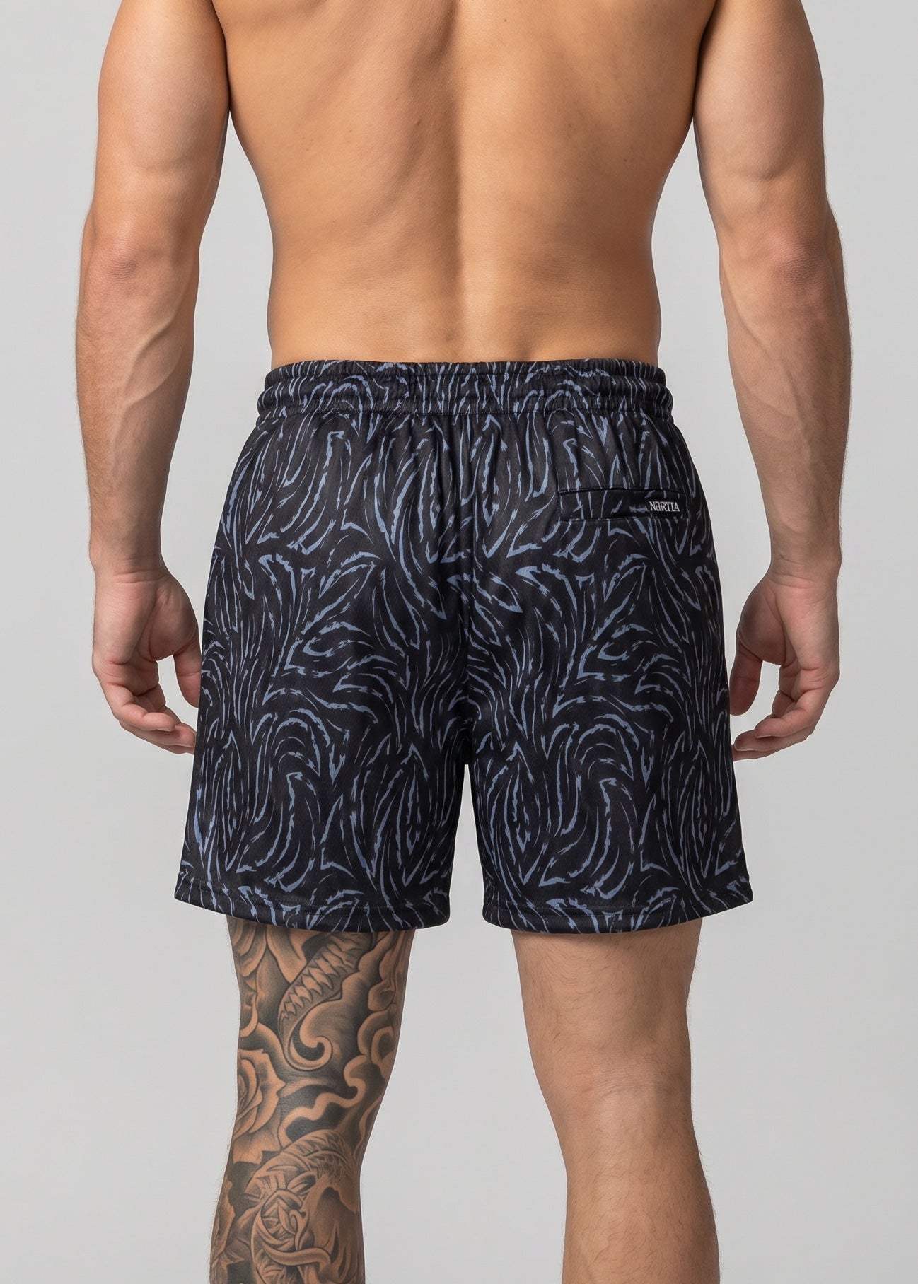 Man wearing navy patterned swim shorts on a light gray background