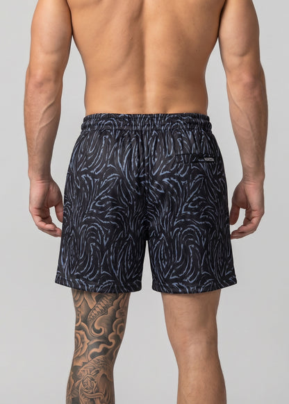 Man wearing navy patterned swim shorts on a light gray background