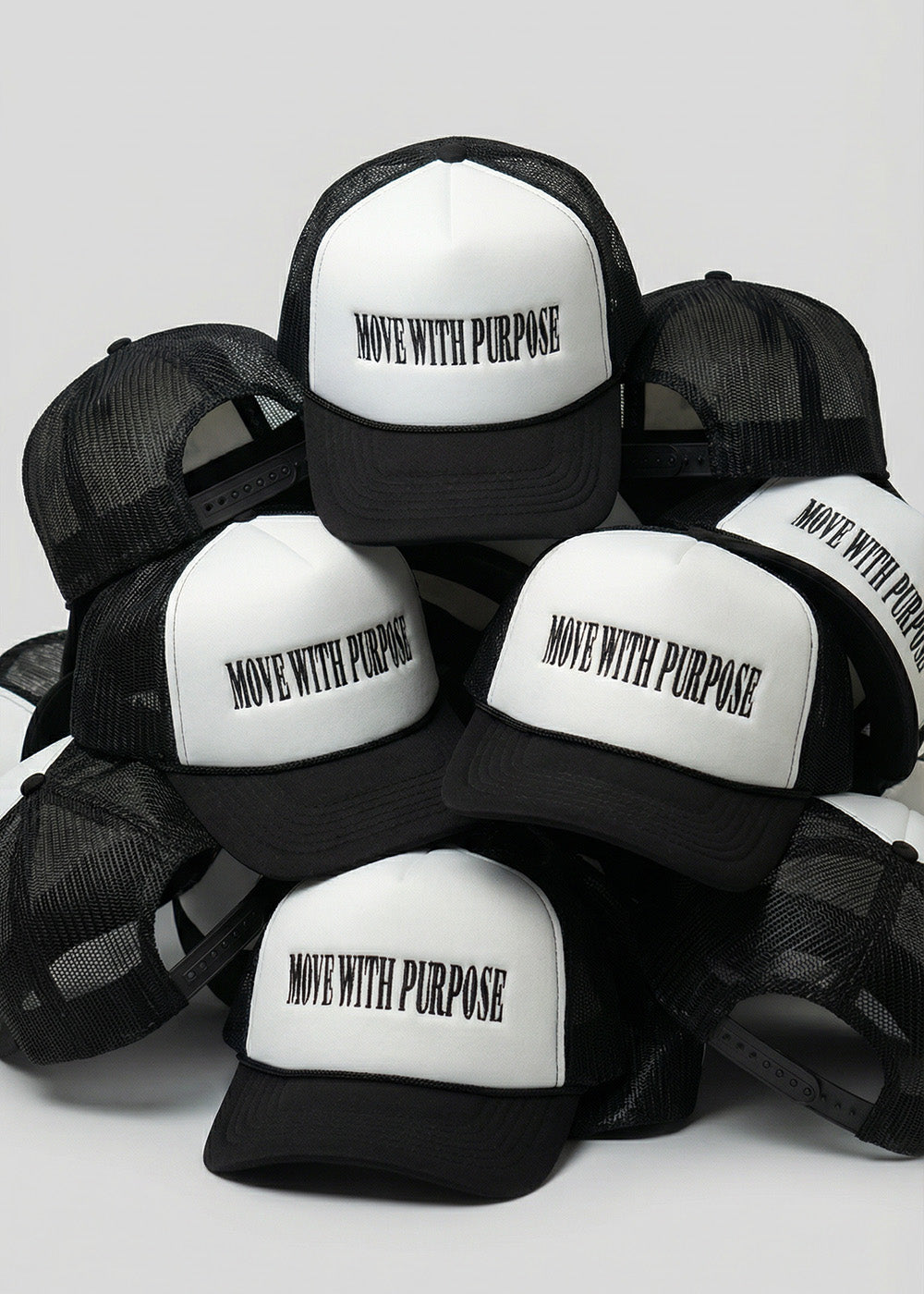 Black and white trucker hats with 'Move with Purpose' text on a light gray background